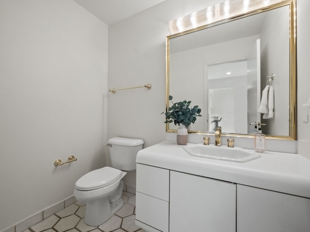half bath with tile patterned flooring, baseboards, toilet, and vanity
