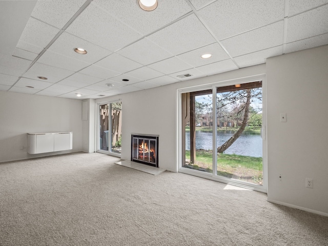 unfurnished living room with visible vents, carpet, a water view, and a paneled ceiling