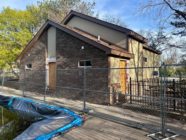 view of side of property with brick siding, a gate, and fence