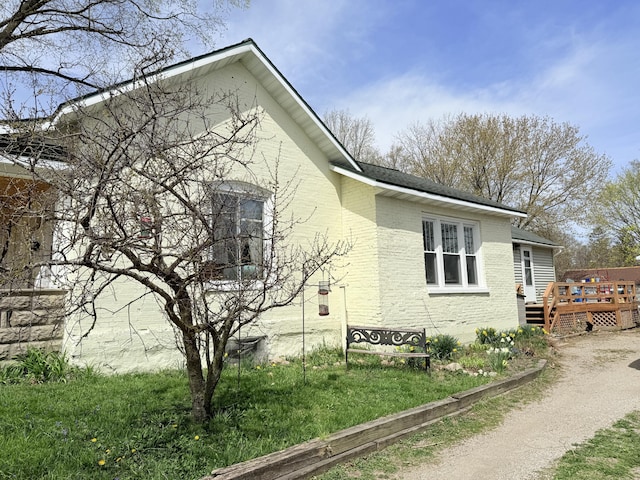 view of home's exterior featuring brick siding, a shingled roof, and a wooden deck