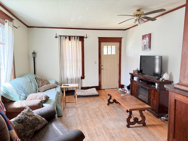 living area with ornamental molding, light wood-style flooring, and ceiling fan