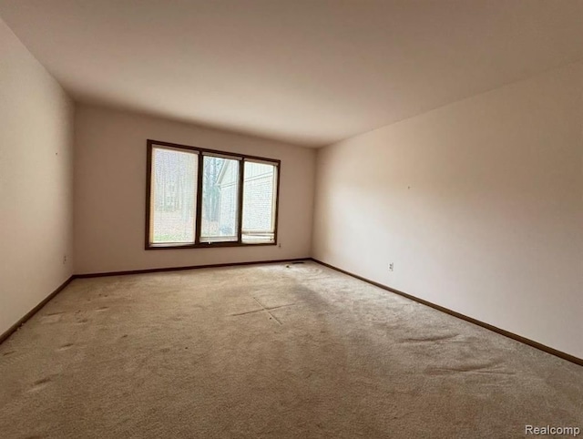 spare room featuring baseboards and light colored carpet