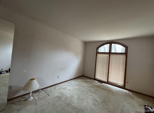carpeted empty room featuring baseboards and visible vents