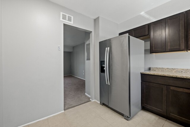 kitchen featuring baseboards, dark brown cabinets, stainless steel refrigerator with ice dispenser, and visible vents