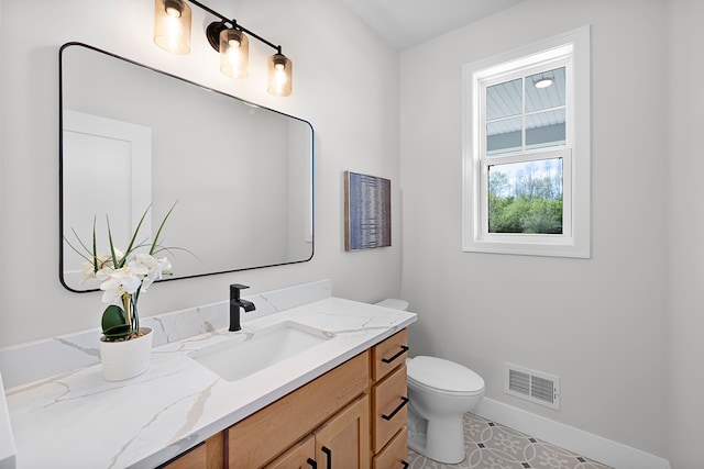 half bath with toilet, baseboards, and vanity