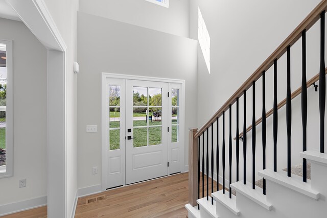 foyer with wood finished floors, stairway, and a high ceiling