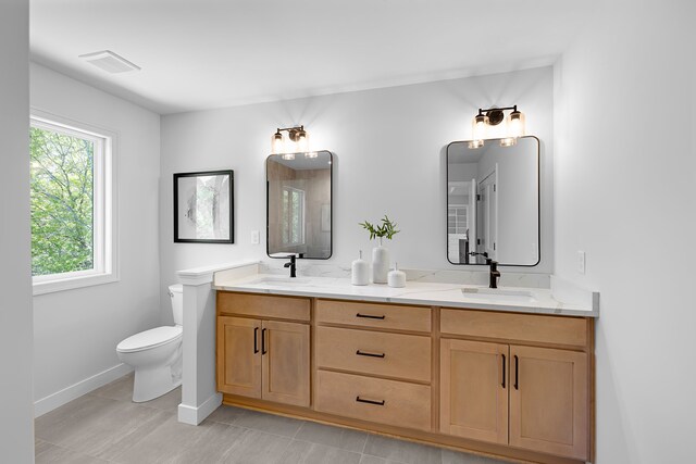 bathroom featuring toilet, double vanity, baseboards, tile patterned floors, and a shower