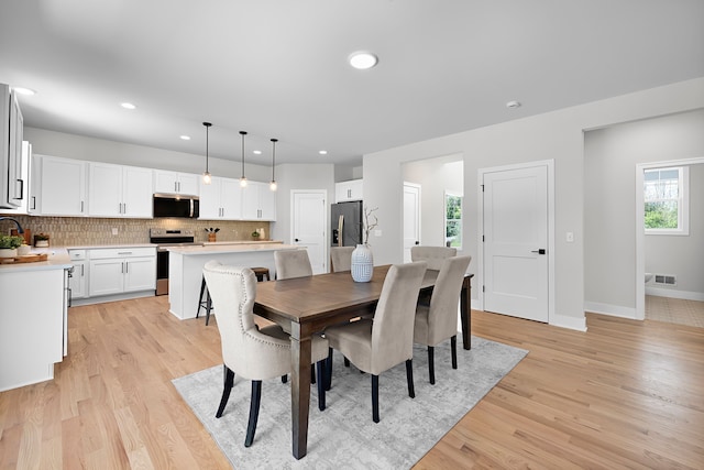 dining room featuring healthy amount of natural light, light wood finished floors, recessed lighting, and baseboards
