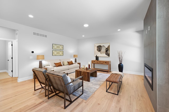 living area featuring light wood-style floors, a large fireplace, recessed lighting, and baseboards