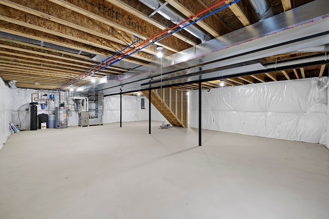 unfinished below grade area featuring stairway, heating unit, and gas water heater