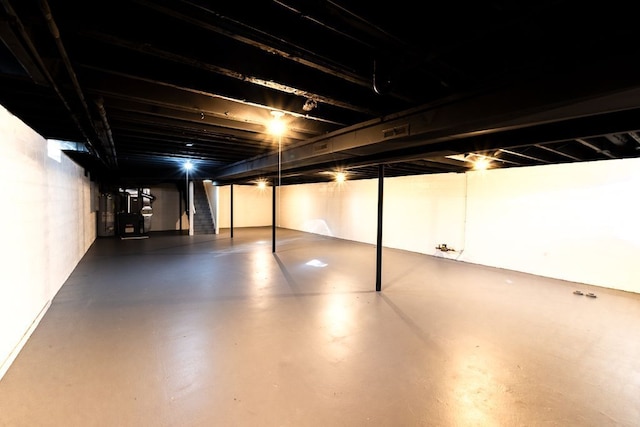 unfinished below grade area featuring visible vents, stairway, and gas water heater