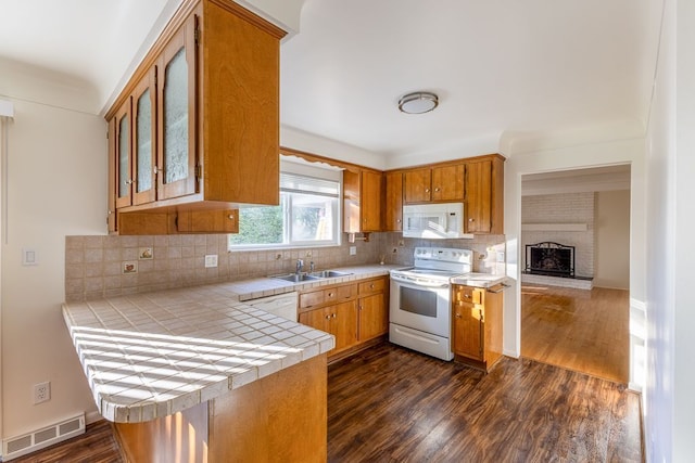kitchen featuring white appliances, tile counters, a peninsula, dark wood-type flooring, and visible vents
