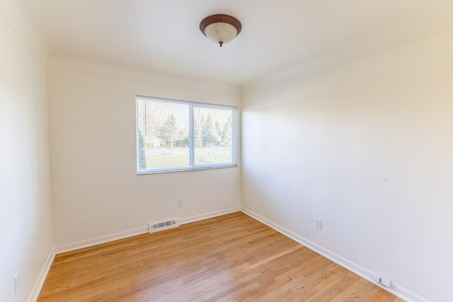 unfurnished room featuring visible vents, light wood finished floors, and baseboards