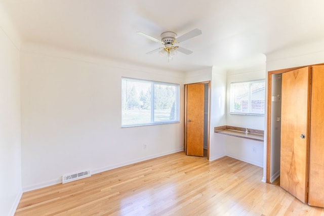 unfurnished bedroom with multiple windows, two closets, light wood finished floors, and visible vents