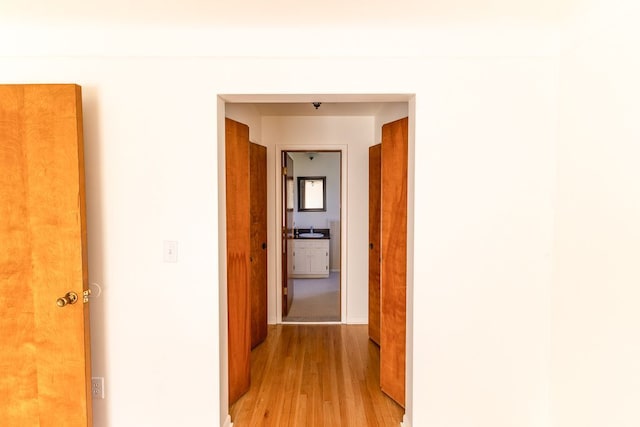 corridor featuring a sink and light wood-style flooring