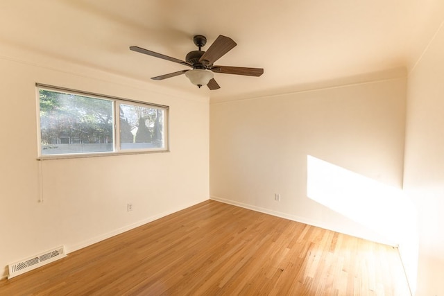 unfurnished room featuring baseboards, a ceiling fan, wood finished floors, and visible vents