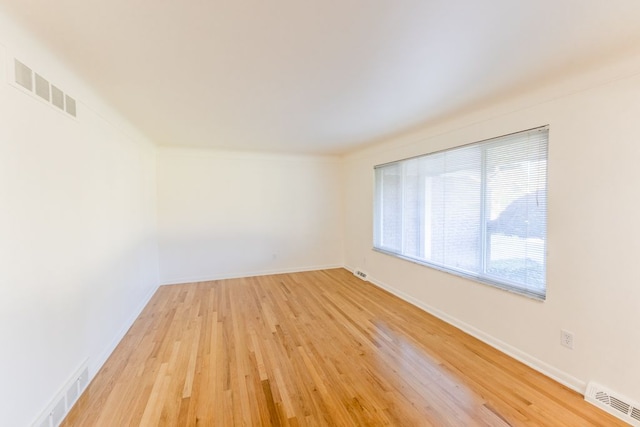 spare room with baseboards, visible vents, and light wood finished floors