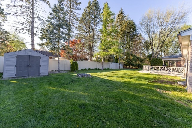 view of yard with a fenced backyard, a shed, an outbuilding, and a wooden deck