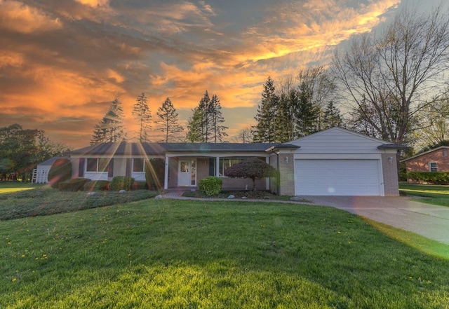 view of front of house with a garage, a yard, driveway, and brick siding