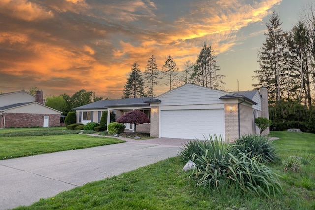 ranch-style house with a garage, a front lawn, a chimney, brick siding, and driveway