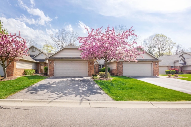 view of front of property with brick siding, an attached garage, a front lawn, and aphalt driveway