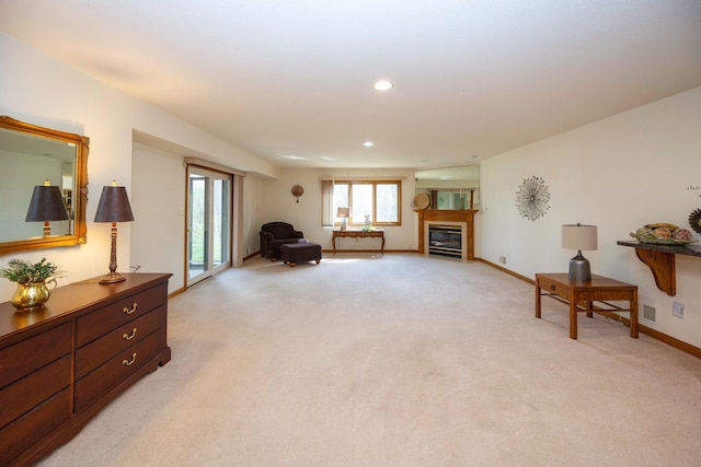 living area with visible vents, a glass covered fireplace, baseboards, light colored carpet, and recessed lighting