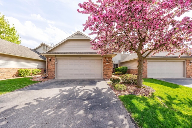view of front of home featuring brick siding, a front lawn, an attached garage, and driveway