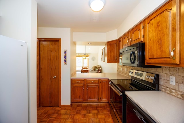 kitchen featuring freestanding refrigerator, black microwave, light countertops, brown cabinets, and stainless steel range with electric cooktop