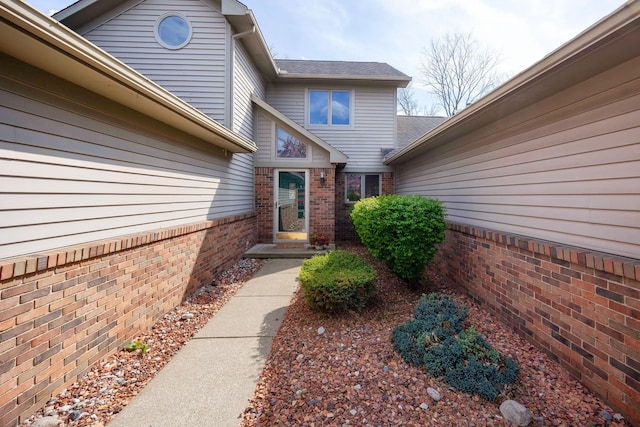 property entrance with brick siding and a shingled roof