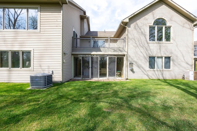 rear view of property with a yard, central AC unit, and a balcony
