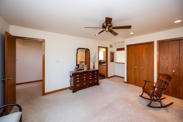 bedroom with baseboards, light carpet, two closets, and visible vents