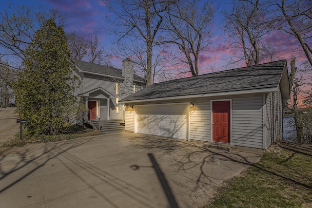 view of front of house featuring a garage, a chimney, and driveway