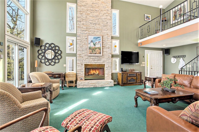 living room with carpet flooring, a stone fireplace, stairs, and a towering ceiling