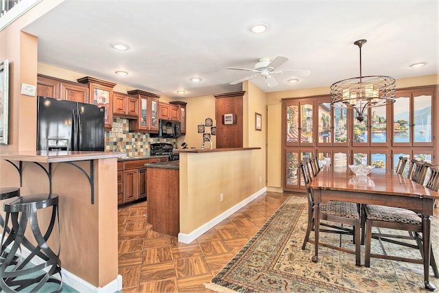 kitchen with baseboards, brown cabinetry, black appliances, and a peninsula