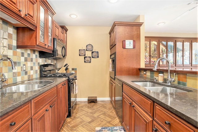 kitchen featuring a sink, dark stone counters, backsplash, and black appliances