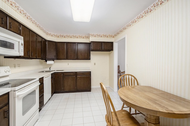 kitchen with light tile patterned floors, dark brown cabinets, white appliances, and wallpapered walls