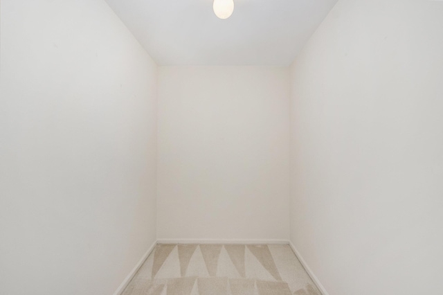 spare room featuring baseboards and light carpet