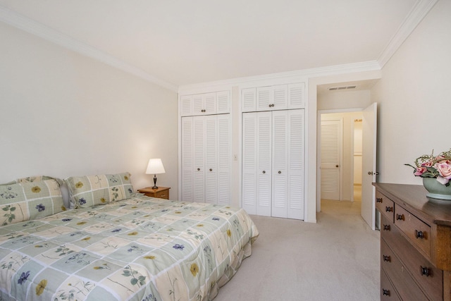 bedroom with two closets, light colored carpet, ornamental molding, and visible vents