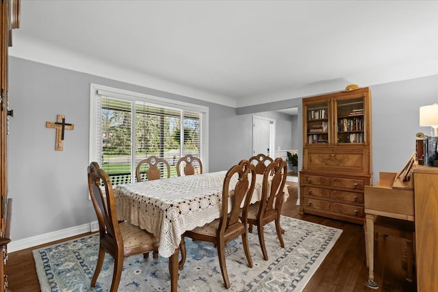 dining space with baseboards and dark wood-type flooring