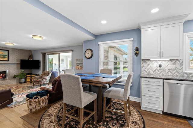 dining area featuring plenty of natural light, a brick fireplace, and dark wood-style floors