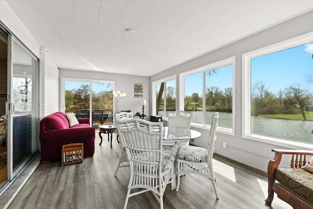 sunroom featuring a water view and wood finished floors