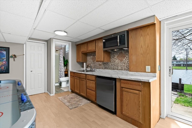 kitchen featuring light wood finished floors, stainless steel microwave, brown cabinets, and refrigerator
