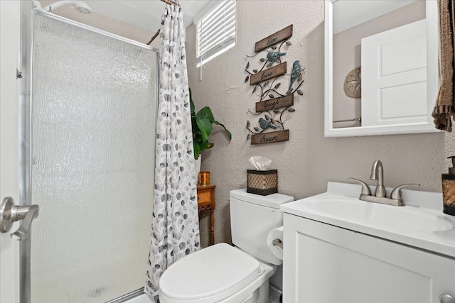 bathroom with vanity, a textured wall, a stall shower, and toilet