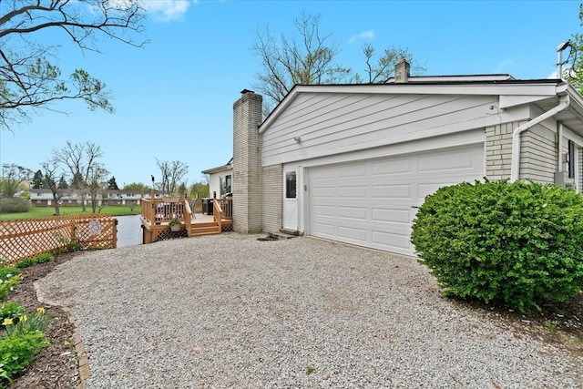 view of home's exterior featuring gravel driveway, fence, a chimney, and a wooden deck