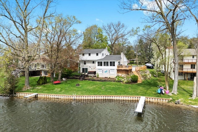 back of house featuring a deck with water view, a chimney, and a lawn