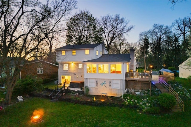 rear view of house featuring a lawn, a deck, a chimney, and stairway