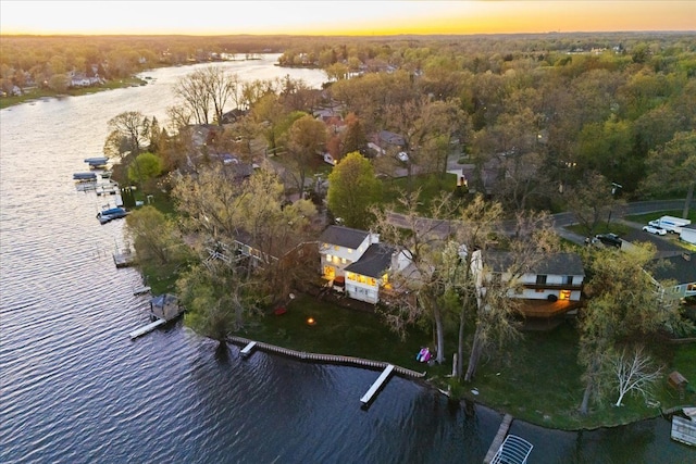 aerial view at dusk with a water view and a forest view