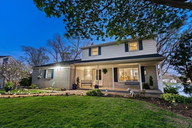 traditional-style house featuring brick siding, a front lawn, and a porch