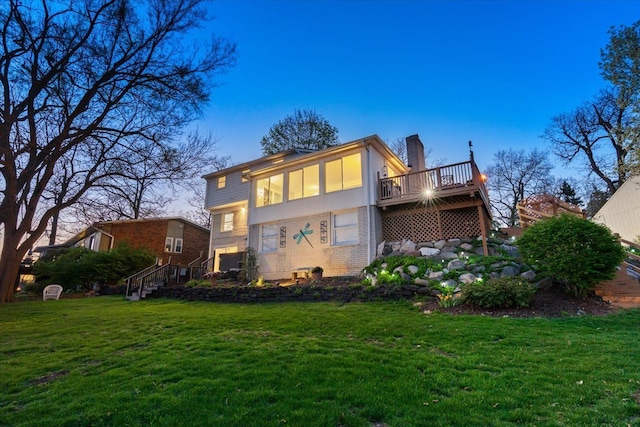 rear view of house featuring a yard, brick siding, a chimney, and a wooden deck