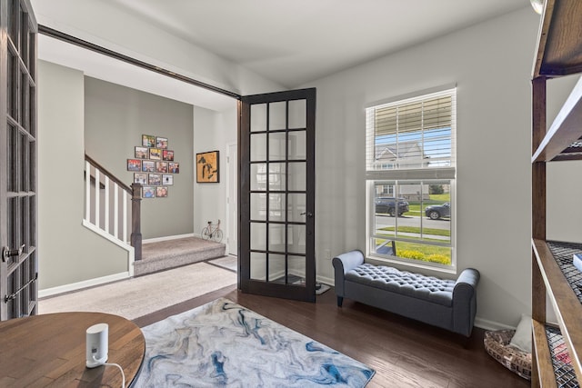 living area featuring french doors, baseboards, wood finished floors, and stairway